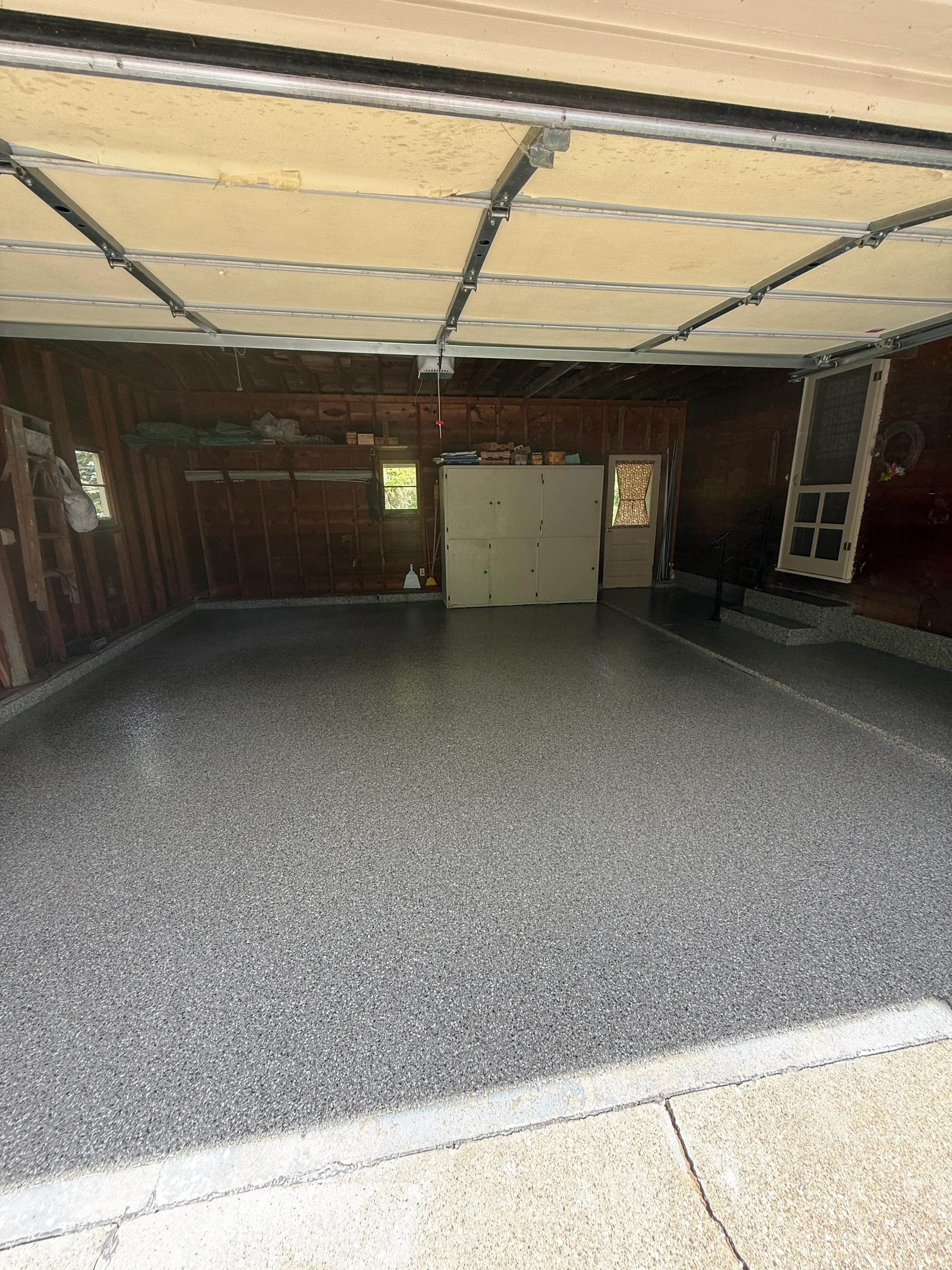 Finished garage floor with gray speckled epoxy coating and overhead door
