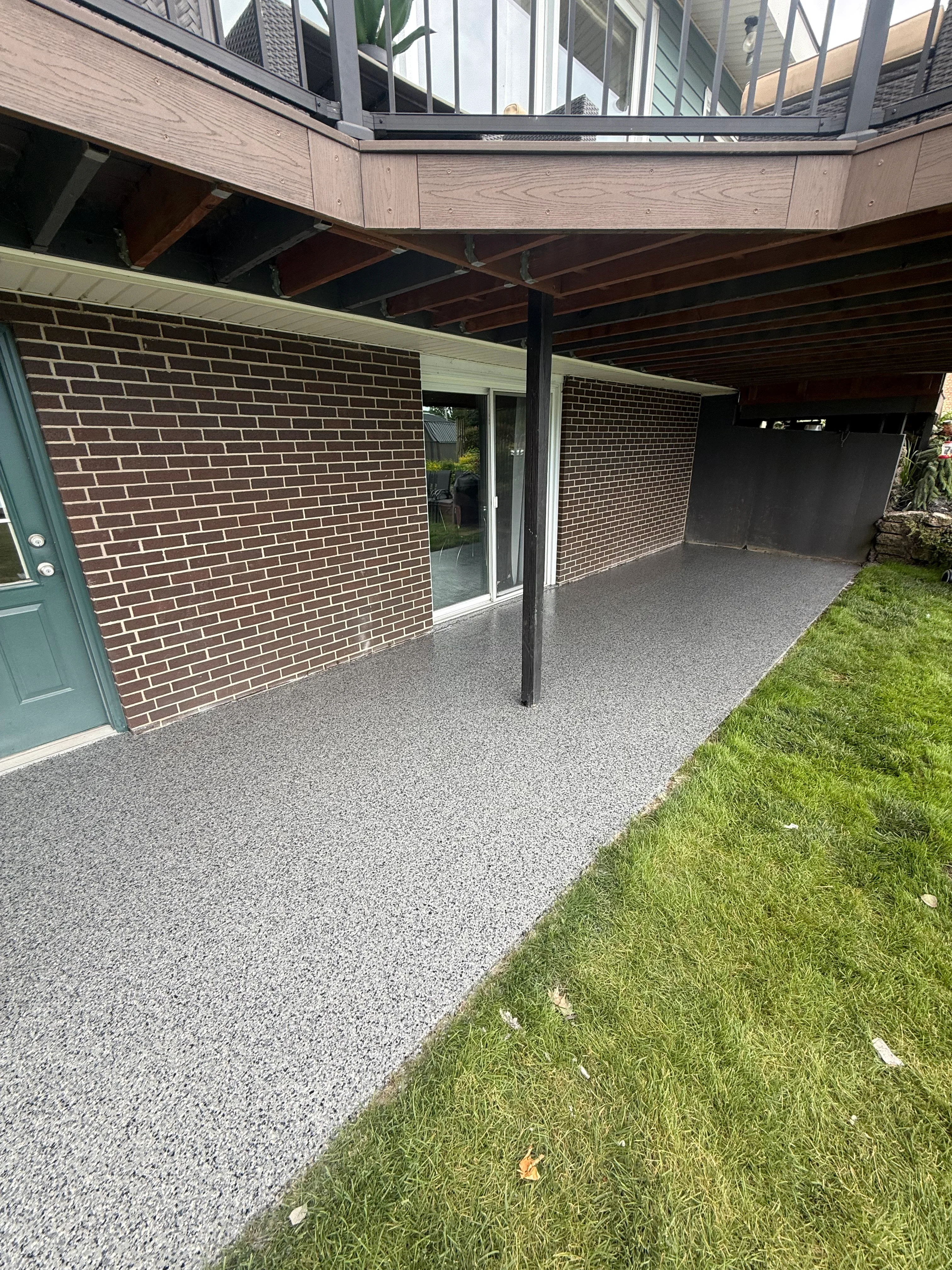 Decorative aggregate concrete patio under covered structure with brick walls and steel posts