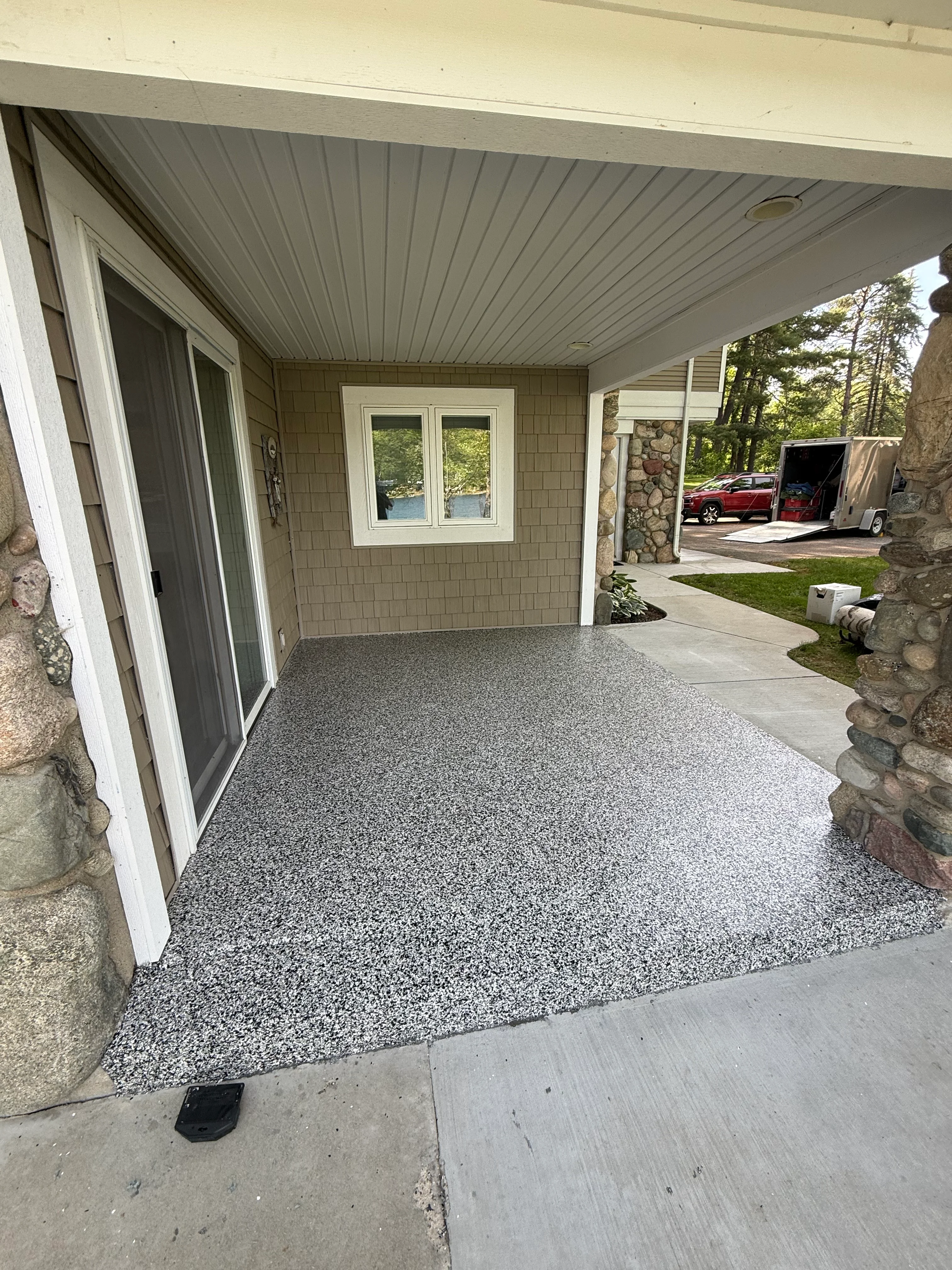 Finished decorative aggregate concrete patio with gray speckled finish under covered porch